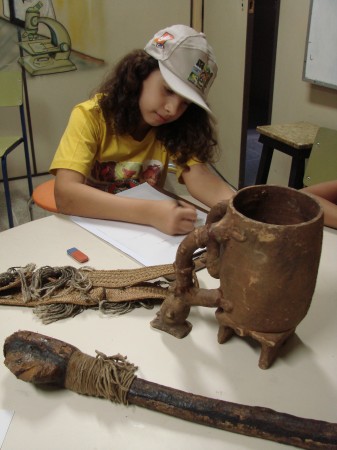 Menina faz anotações sobre peça arqueológica
