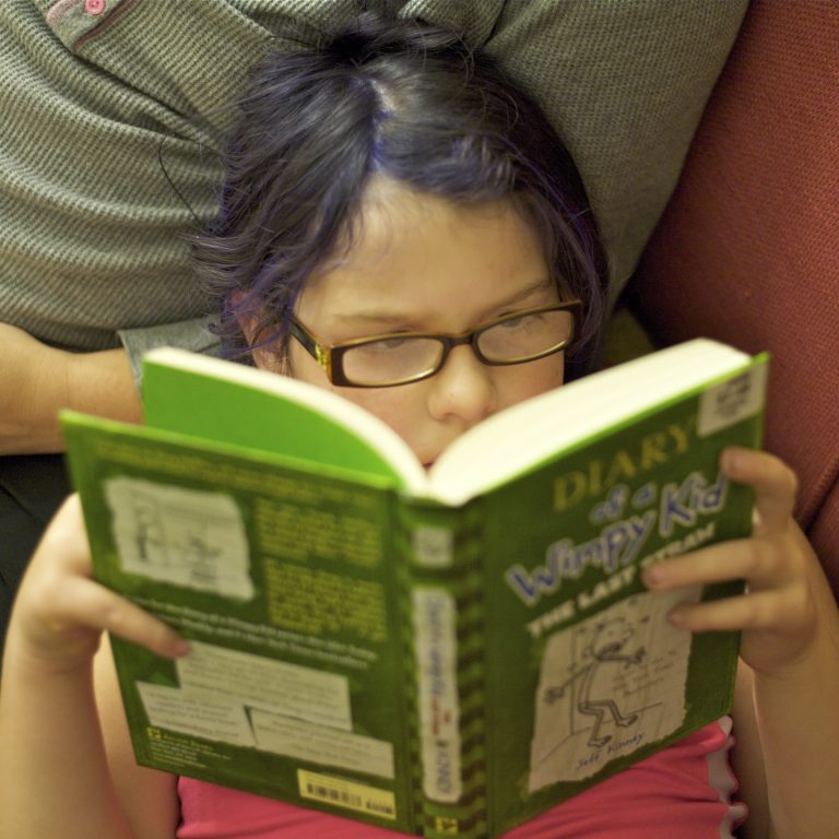 Menina de óculos lendo um livro